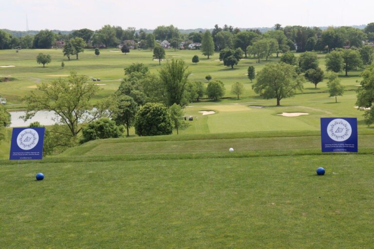A scenic golf course featuring a lush green grass field under a clear blue sky