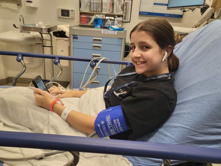A child in a hospital bed, equipped with a blood pressure cuff, appearing relaxed while receiving medical care
